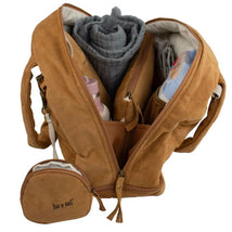 Doudoune changing bag in camel color, featuring multiple compartments filled with a rolled blanket, a bottle, and other baby essentials.