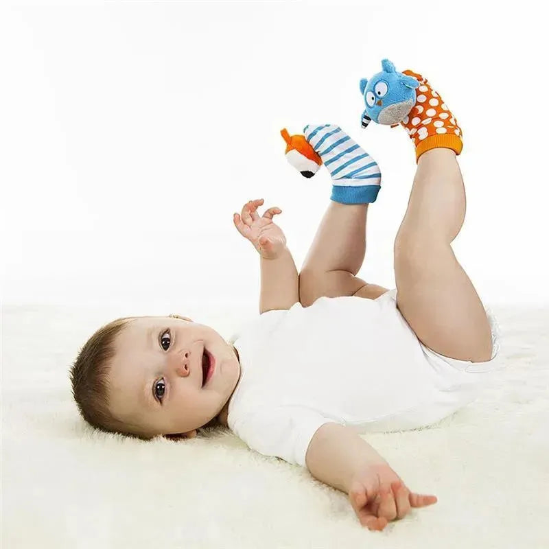Baby lying on a soft surface, wearing a white onesie, with colorful foot finders featuring a blue owl and an orange fox on their feet.