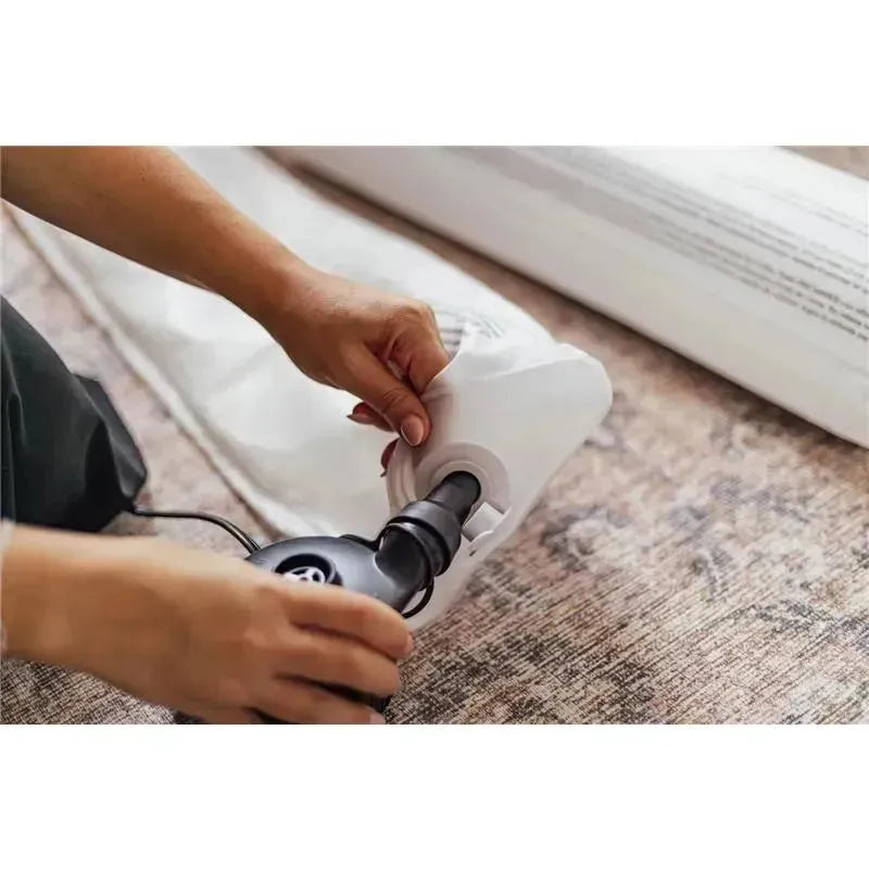 Hands connecting an air pump to a Bbluv inflatable bed bumper on a textured surface.