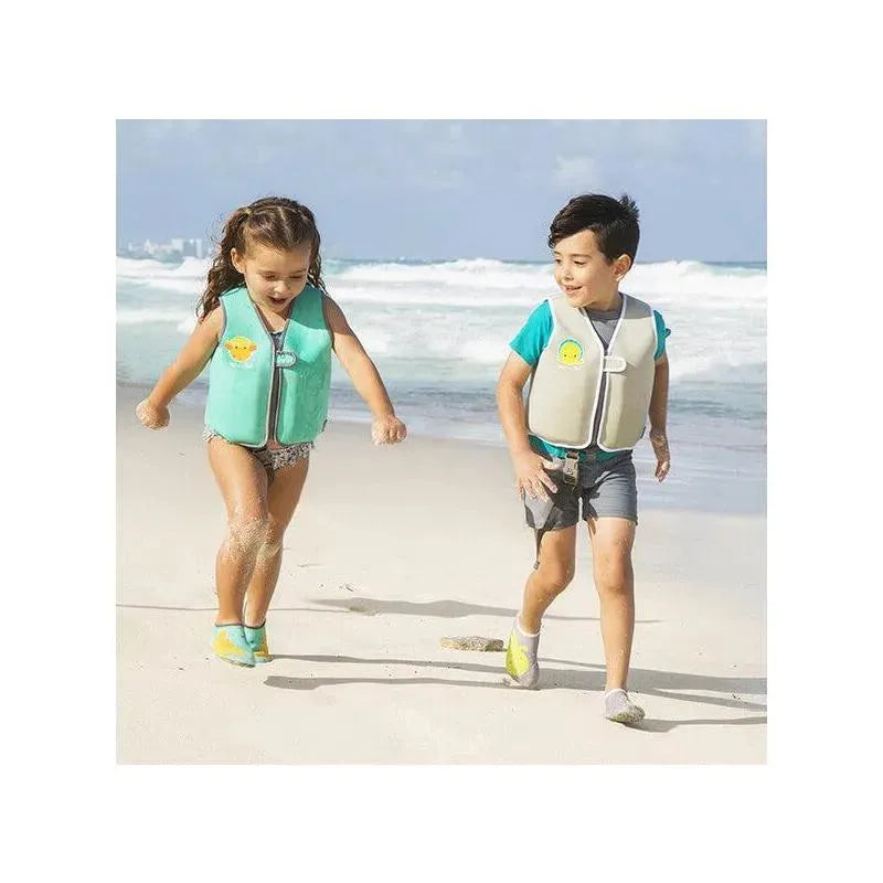 Children playing at the beach, wearing Bbluv Naj swim vests, with a sunny shoreline in the background.