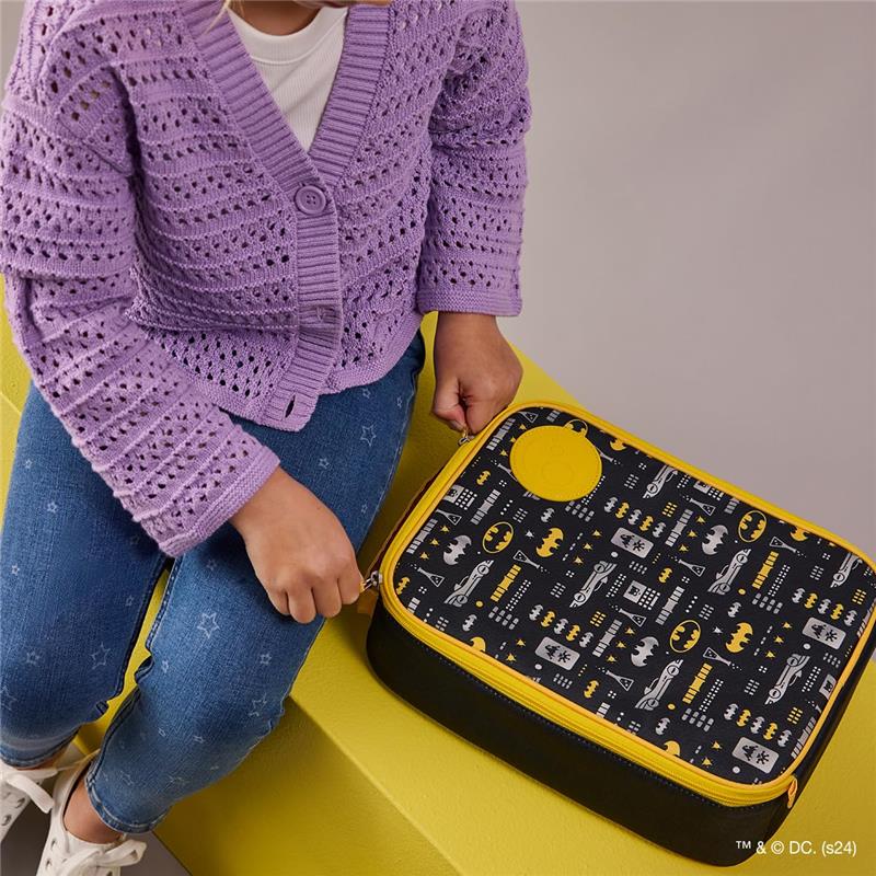 Batman-themed insulated lunch bag with a yellow zipper, held by a child wearing a purple cardigan and blue jeans.
