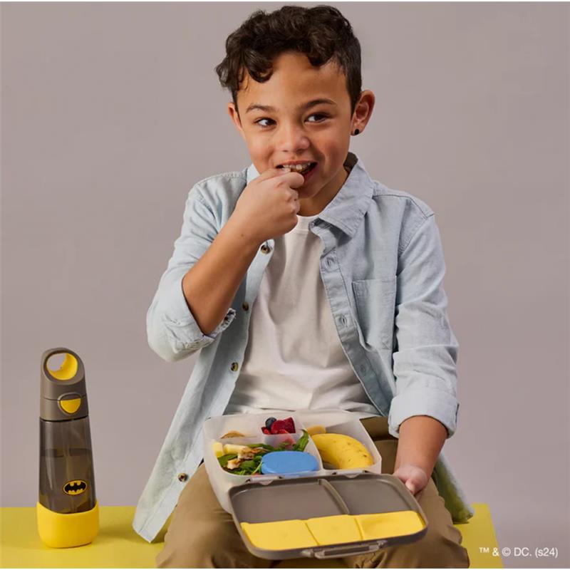 Child enjoying a snack from a Batman-themed jumbo bento lunchbox, with a water bottle nearby.