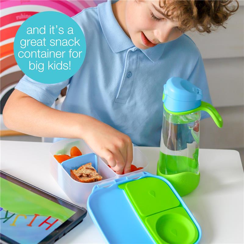 Child in a blue polo shirt uses the Bbox Mini Lunch Box, filled with carrot sticks and bread, alongside a green water bottle.