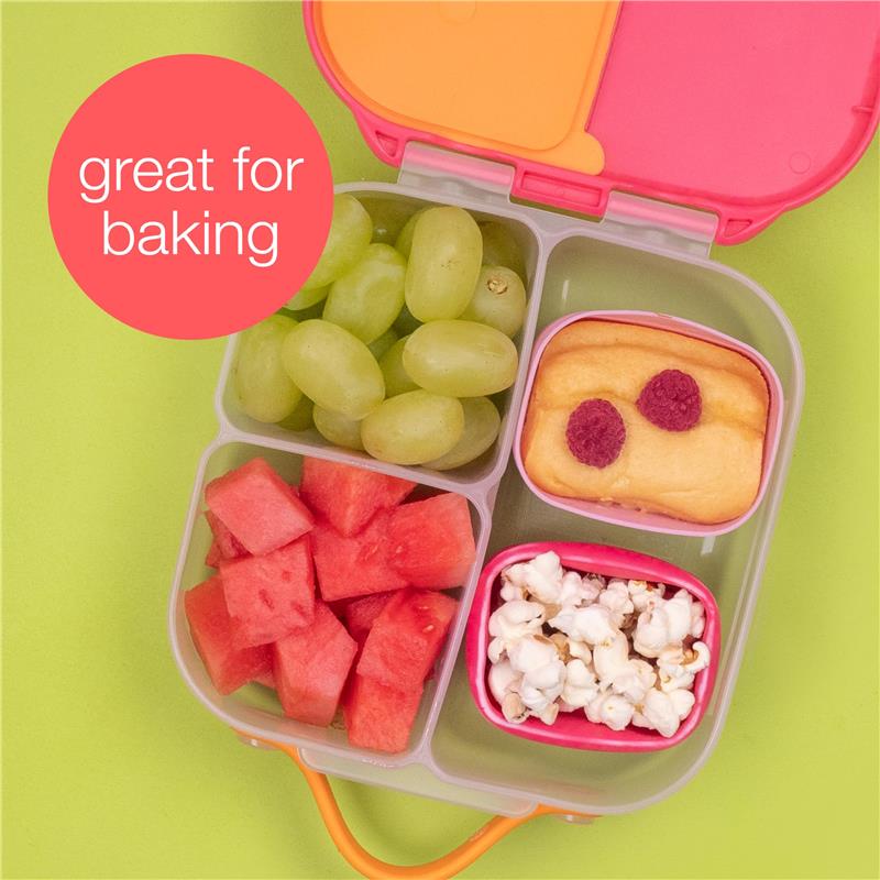 Silicone snack cups filled with grapes, watermelon, popcorn, and a baked treat, on a green background.