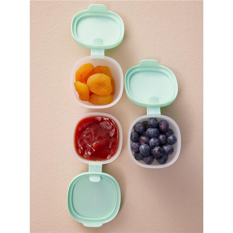 Silicone snack tubs in berry colors containing dried apricots, ketchup, and blueberries, set against a light background.