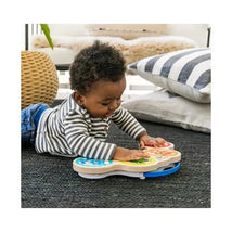 Toddler playing with the Be Hape Magic Touch Drum, featuring colorful animal designs, in a cozy indoor setting.