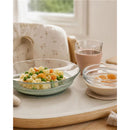 Glass meal set featuring a plate of pasta with peas and carrots, alongside two bowls of fruit and yogurt.