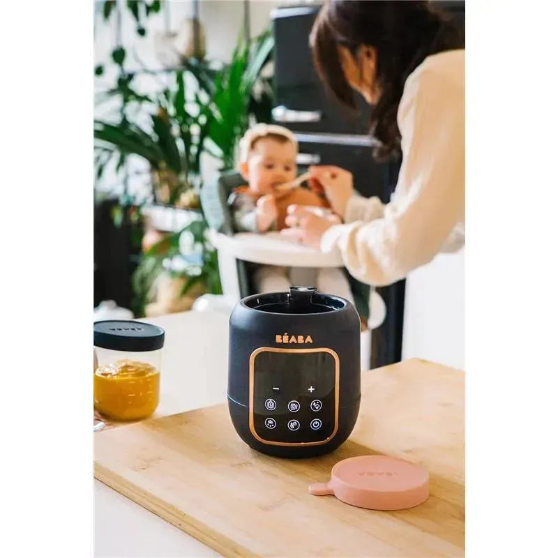 Beaba 5-in-1 Multi Milk Baby Bottle and Food Warmer in midnight color, with digital control panel, on a wooden surface.