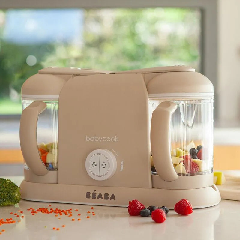 Beaba Babycook Duo in Oat color with two transparent bowls, featuring fruits, vegetables, and a control knob.