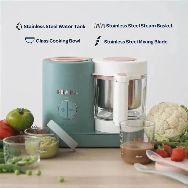 Beaba Babycook Neo baby food maker in eucalyptus color with glass bowl, stainless steel components, and fresh vegetables nearby.