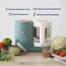 Beaba Babycook Neo baby food maker in eucalyptus color with glass bowl, stainless steel components, and fresh vegetables nearby.