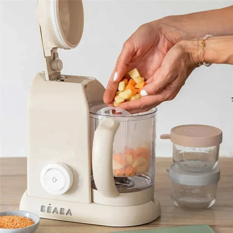 Beaba Babycook Solo, a beige 4-in-1 baby food maker, is shown with chopped fruits being added.