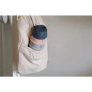 Beaba Formula and Snack Container in rose color, featuring stacked grey, pink, and blue compartments, hanging in a pocket.