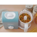 Beaba Rice, Pasta, & Grain Insert in a food processor with colorful pasta visible inside, featuring a blue base and white handle.