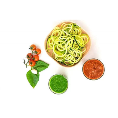 Bowl of spiralized zucchini noodles with red and green sauces, cherry tomatoes, a garlic clove, and basil leaves on a white background.