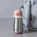 Stainless steel kids water bottle in rose color with a pink lid and white accents beside a light gray backpack.
