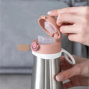 Stainless steel kids water bottle in rose; lid is open with a clear silicone spout exposed.