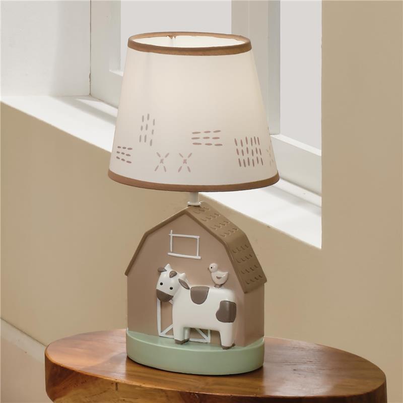 Decorative nursery lamp featuring a cow and bird design on a barn-shaped base with a soft-lit shade.