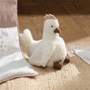 Plush chicken stuffed animal toy with a fluffy white body, brown feet, and a small crest, placed on a textured mat.