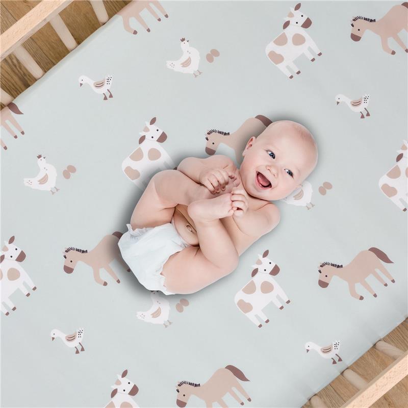 Sage green crib sheet with farm animal patterns featuring a smiling baby in a diaper, lying comfortably.