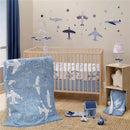 Plush airplane-themed nursery set featuring a crib with bedding, a soft blanket, and decorative accents.