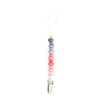 Colorful silicone beads in purple, pink, and orange form a Bella Tunno pacifier clip with a metal attachment.