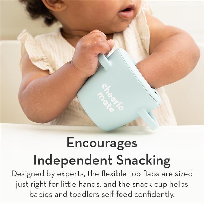 Silicone snack cup for toddlers in light blue, held by a child, with text highlighting independent snacking and flexible top flaps.