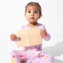 Child wearing pink patterned pajamas holds an open card featuring a Hogwarts crest.