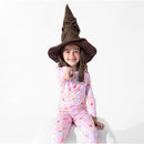 A child wearing a Sorting Hat points a toy wand while dressed in colorful Harry Potter-themed pajamas.