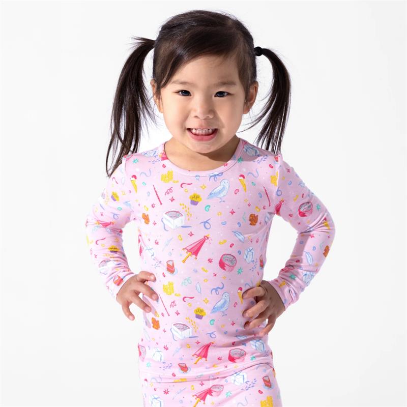 Bamboo kids pajamas featuring a pink fabric with colorful Harry Potter-themed designs, worn by a smiling girl.