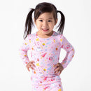 Bamboo kids pajamas featuring a pink fabric with colorful Harry Potter-themed designs, worn by a smiling girl.