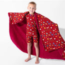 A child in a red patterned outfit holds a soft, red bamboo blanket featuring Harry Potter-themed designs.