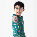Child in colorful Harry Potter-themed bamboo pajamas featuring mandrakes and herbs, playfully pointing a wand.
