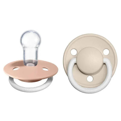 Two BIBS premium pacifiers in Blush Night and Vanilla Night colors, featuring round shields and silicone nipples.