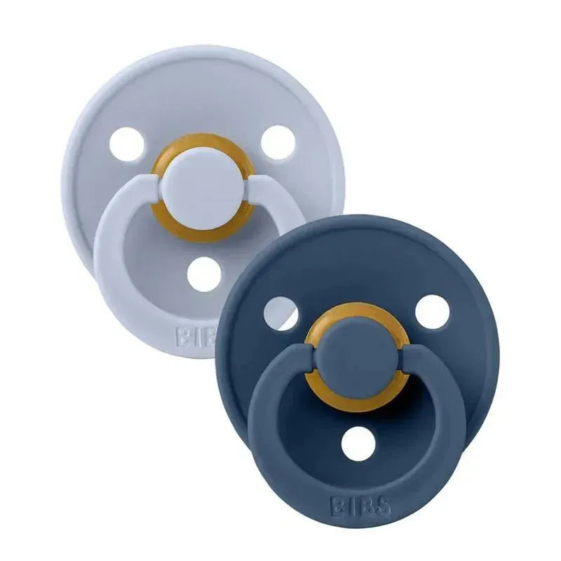 Two natural rubber baby pacifiers in dusty blue and steel blue, featuring a gold-colored shield and ventilation holes, suitable for ages 6-18 months.