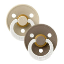Two BIBS rubber baby pacifiers in Vanilla and Dark Oak colors, designed for infants 0-6 months, featuring a round shield and handle.