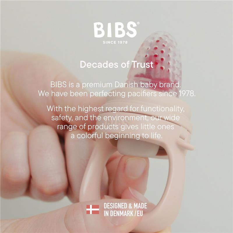 BIBS baby feeder in Fossil Grey, featuring a textured pink silicone tip and sturdy handle, held in a hand.