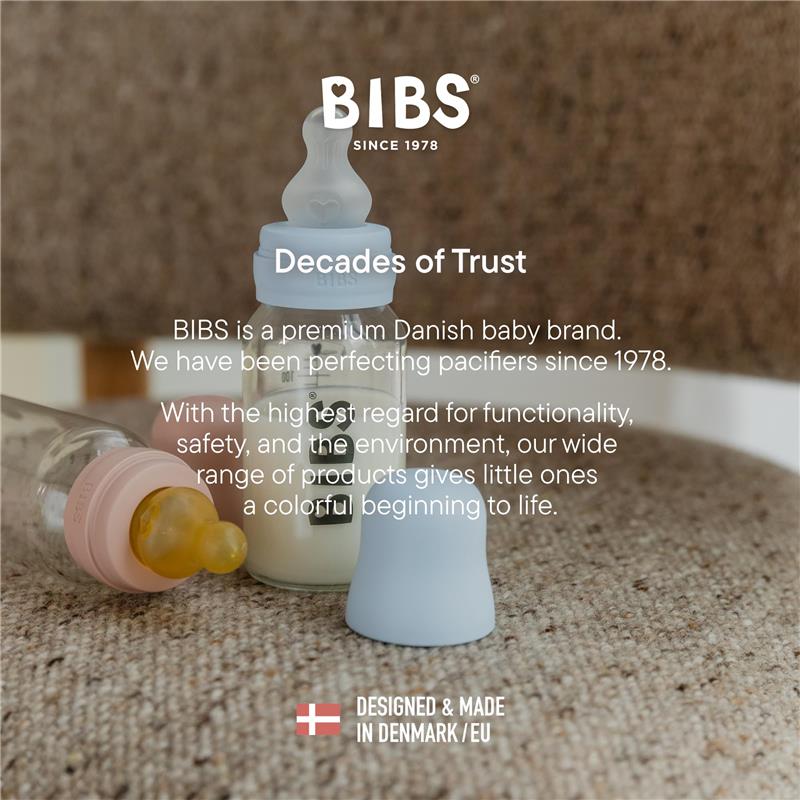 Baby Blue plastic bottle with latex nipple by Bibs, designed for infants, placed on a textured surface next to a pink bottle.