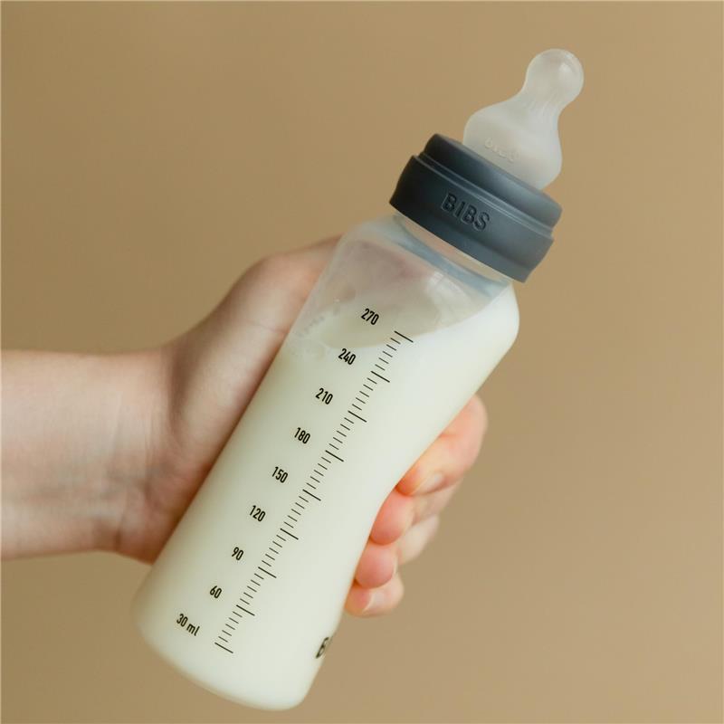 Bibs baby bottle in sage color, 270ml, held by a hand, filled with liquid, featuring measurement markings.