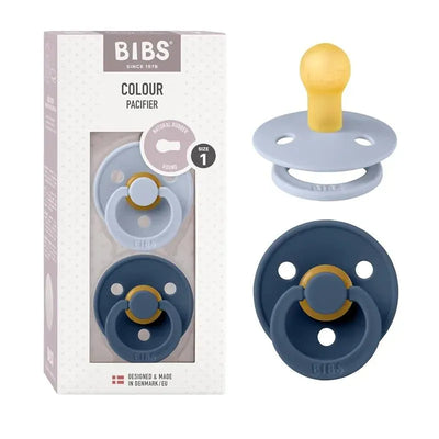 Two-pack of BIBS pacifiers in Dusty Blue and Steel Blue, featuring round natural rubber nipples, displayed with packaging.