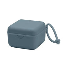 Square petrol-colored pacifier box with a closure and a loop for easy carrying.