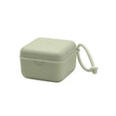 Square sage green pacifier box with a lid and attached strap, designed for storing pacifiers safely.