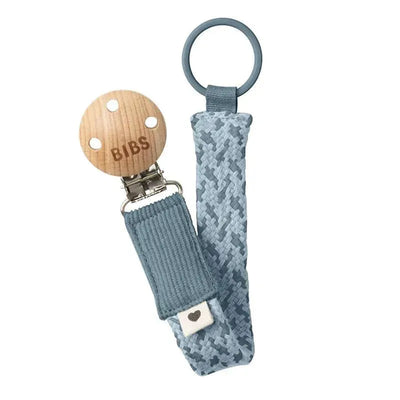 Bibs pacifier clip in petrol and baby blue, featuring a wooden clip and textured fabric strap.