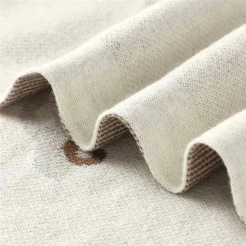 Luxury cotton receiving swaddle baby blanket in cream color with subtle car print details and textured waves.