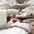 Baby feet peeking out from under a soft cream-colored swaddle blanket with a cars pattern, showcasing a cozy scene.