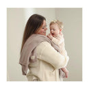 Luxury cotton swaddle receiving blanket draped on a woman holding a smiling baby, both in soft, neutral colors.