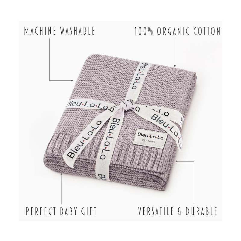100% organic cotton swaddle blanket in soft lavender, featuring a decorative ribbon and text indicating washability and versatility.