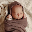 Luxury organic blanket and bonnet hat set in blue, with a sleeping baby swaddled in the blanket.