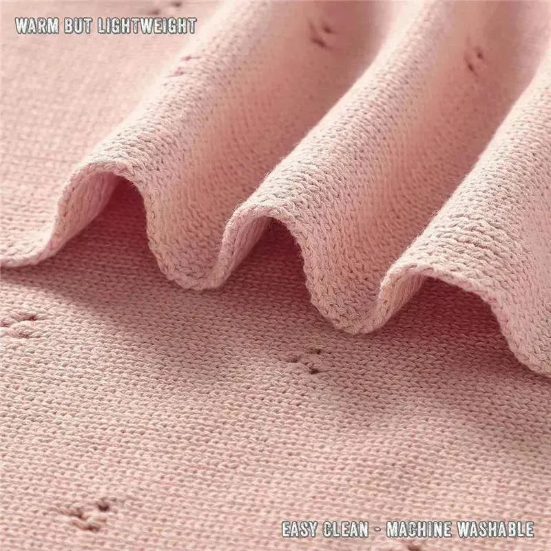 Organic cotton pointelle swaddle blanket in soft pink, showcasing its lightweight texture and gentle folds.