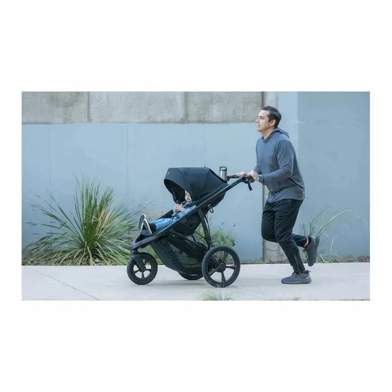Jogging stroller BOB – Wayfinder, Nightfall model, being pushed by a man while jogging, with a child inside.